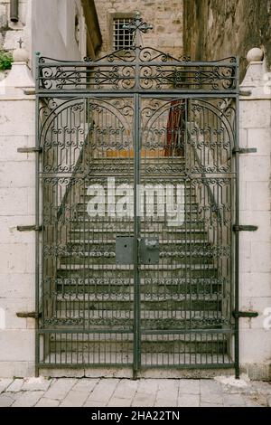 Metal gate at the entrance to the church with a cross on top Stock Photo