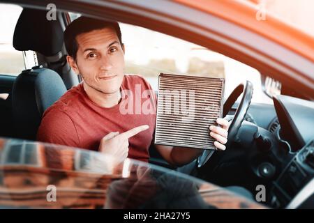 Man changes old polluted filter for the ventilation of the car interior. Dangerous particles of pollen, bacteria and viruses are collected in the air Stock Photo