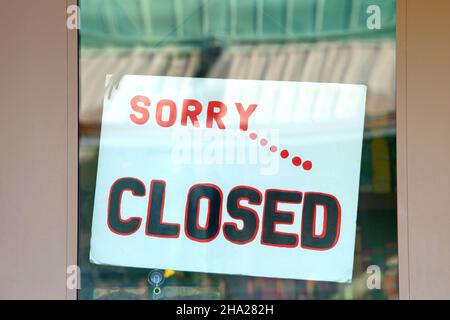 Close up on Sorry... Closed sign in glass window on brown wood door. Many businesses remain closed due to the Covid 19 pandemic and resurgence due to Stock Photo