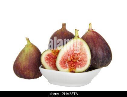 Fresh organic figs in and around a small white bowl, one sliced in half showing inside. Isolated on white. Stock Photo