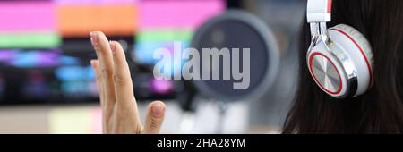 Woman radio presenter sits in front of monitor with headphones closeup Stock Photo