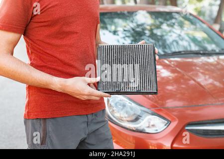 Man changes old polluted filter for the ventilation of the car interior. Dangerous particles of pollen, bacteria and viruses are collected in the air Stock Photo