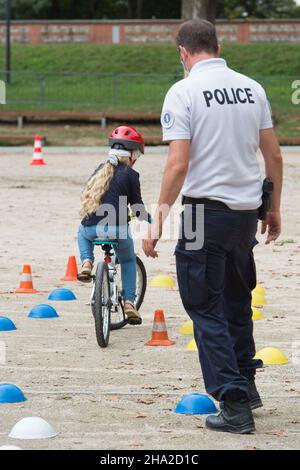 Road safety activity: child on a bike and police officer Stock Photo