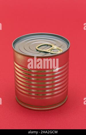 Unopened Tin Can with Blank Edge on Red Background. Canned Food. Aluminum Can for Safe and Long Term Storage of Food. Steel Sealed Food Storage Container Stock Photo