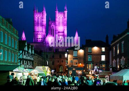 Lincoln Cathedral is floodlit for the annual Christmas market. Visitors pack the maarket between the Cathedral and the castle..The market returning after being cancelled the previous year due to Covid 19 is one of the largest Christmas markets in Europe. Centred in and around the catle and the Cathedral in the Bailgate area of Lincoln the markets draws visitors from all over Europe. Stock Photo