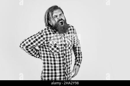 brutal bearded man wear checkered shirt having lush beard and moustache feel pain in back, medicine Stock Photo