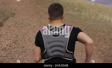 Caucasian male runner runs up steep dusty trail in dry mountains. Athlete during intense running workout in mountains. Man runs uphill. Stock Photo