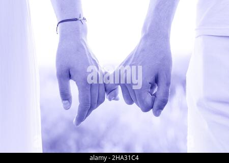 A guy and a girl are holding hands with littles in nature. Color of the Year 2022 - Very Peri. Stock Photo