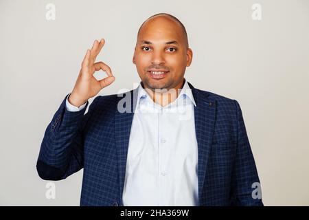 Young african american man smiling positively, making okay hand and fingers sign. Lucky expression. Black man feeling successful and contented Stock Photo