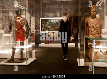 10 December 2021, North Rhine-Westphalia, Essen: A trade visitor looks at the magnificent armour of Duke Wilhelm V of Jülich-Kleve-Berg (1555) and the statue of Archbishop Engelbert of Cologne (1235) in the exhibition 'A class of its own. Nobility on the Rhine and Ruhr'. From 13 December 2021, the special exhibition will provide an overview of the entire history of the nobility on the Rhine and Ruhr from the early Middle Ages to the present day. Photo: Roland Weihrauch/dpa - ATTENTION: Only for editorial use in connection with a report on the exhibition and only with full mention of the above Stock Photo