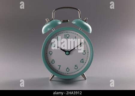 Turquoise alarm clock at ten o'clock on gray background. Time control concept Stock Photo
