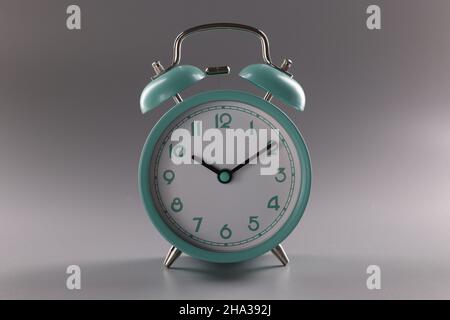 Turquoise alarm clock at ten o'clock on gray background. Time control concept Stock Photo
