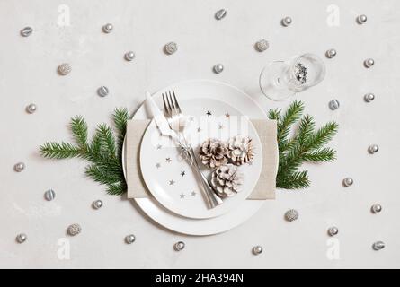 Christmas table setting with silver decorations on a gray background. Top view, flat lay. New Year party. Stock Photo