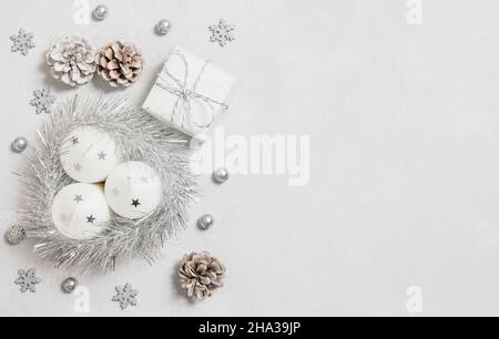 Christmas silver decorations on gray background. Christmas border with candles, shiny tinsel, gift and cones. Greeting card. Copy space, template. Top Stock Photo