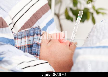 Man with clinical thermometer in his mouth sleepy, bed cover, measure, mouth, head, face, Stock Photo