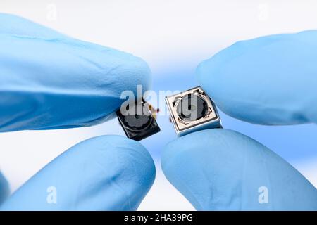 Two cell phone camera modules in scientist hands. Stock Photo