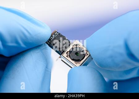 Two cell phone camera modules in scientist hands. Stock Photo