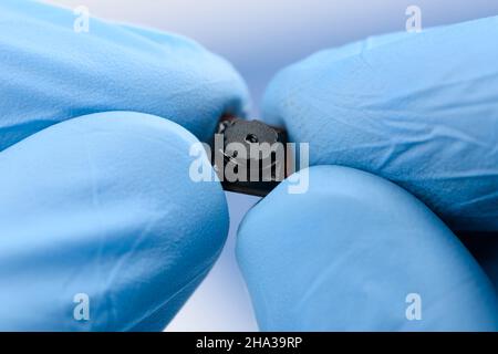 Tiny cell phone camera module in hands. Camera sensor technology research. Stock Photo