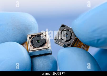 Two camera modules in scientist hands. Different sensor and technology smartphone new high resolution cameras in laboratory. Stock Photo