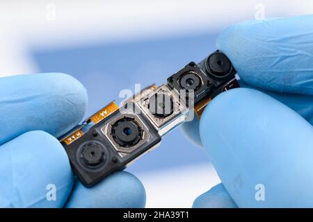 Camera modules with different sensor technology and resolution in scientist hands. Smartphone cell phone cameras research or repair concept in laborat Stock Photo