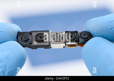 Camera modules in scientist hands. Different sensor and technology smartphone small cameras in laboratory. Stock Photo