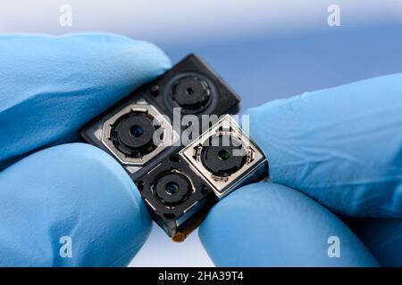 Smartphone camera modules in scientist hands. Different sensor sizes and technology used. Stock Photo