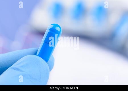 Scientist hold in hand blue pill capsule. New medical treatment or supplement laboratory scientific research. Stock Photo