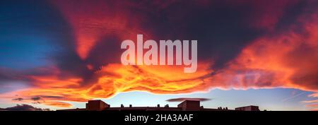 A large cloud with curious wavy shapes and warm reddish colors during a sunset sky background. Stock Photo