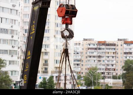 Crane hook. Tower Crane Hoist Rope against the blue sky and new building. Hawser of winch. Crane lifting cables. Construction site. Construction Stock Photo