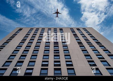 looking upwards at an office building with a plane flying over. fly away concept. Stock Photo