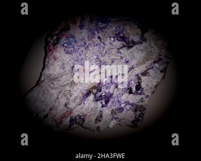 Close-up on a pegmatite rock, with vibrant colors in dark pink tones. Crystal seen under the microscope. Top view, abstract background. Stock Photo