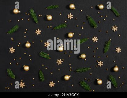Christmas pattern with fir branches, golden baubles and snowflakes on a black background. New Year composition. Greeting card. Top view, flat lay. Stock Photo