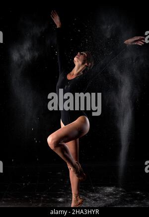 Dramatic portrait of young, strong and talented female dancer with white powder explosion, moving in dust, flour. Graceful caucasian slim gorgeous wom Stock Photo