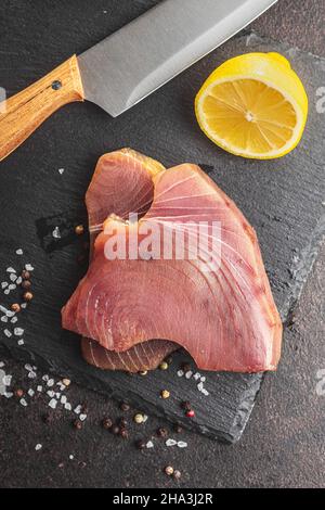 Raw tuna steak. Raw fish meat on black table. Top view. Stock Photo