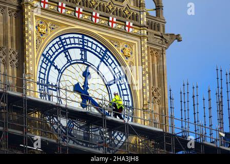 London, UK. 10th Dec, 2021. Workmen walk past the clockface of Big Ben as the scaffolding is gradually removed after renovations Stock Photo