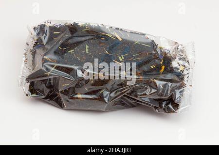 Black tea packaging on a white background. Long leaf tea with rose hips, apples and flower petals, packed in a transparent package. Tea with a fruity Stock Photo