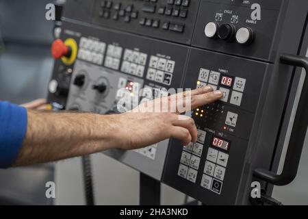 man pressing a button in a cnc lathe control panel Stock Photo