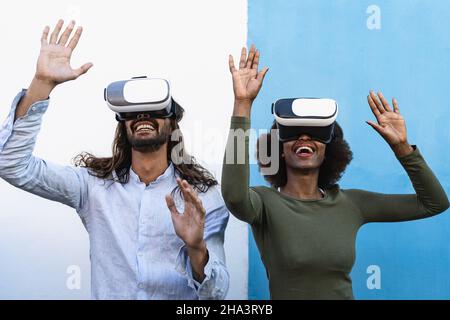 Happy friends having fun playing with innovated virtual reality glasses - Tech gaming entertainment and metaverse concept Stock Photo