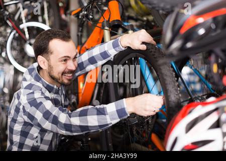 Man in sports workshop mounts bike using special tools Stock Photo