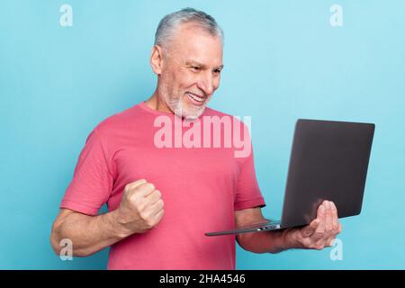 Photo portrait elder man smiling using laptop browsing internet gesturing like winner isolated pastel blue color background Stock Photo