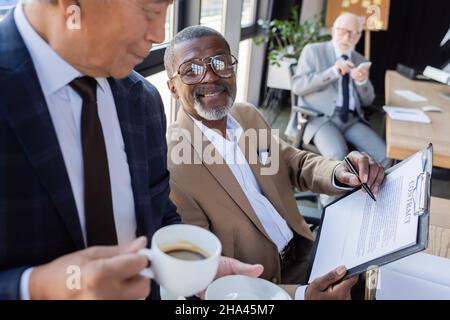 african american businessman pointing at contract near multiethnic ...