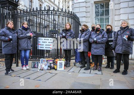 Westminster, London, UK. 10th Dec, 2021. A group of women from 'Covid-19 Bereaved Families for Justice' protest outside the gates to Downing Street with cheese and wine, against the alleged Christmas Party which may have taken place with cheese and wine at Downing Street last Christmas. The women, all volunteers at the National Covid Memorial Wall, have brought along pictures of loved ones who died from covid, and are also there to remind the government of the many people who died unecessarily, in their view. Credit: Imageplotter/Alamy Live News Stock Photo