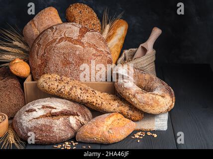 Assortment of fresh rye and wheat bread on a dark background. Side view, copy space. Stock Photo