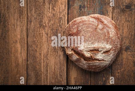 A loaf of fresh rye bread on a wooden table with space for copying. Minimalistic bread background. Stock Photo