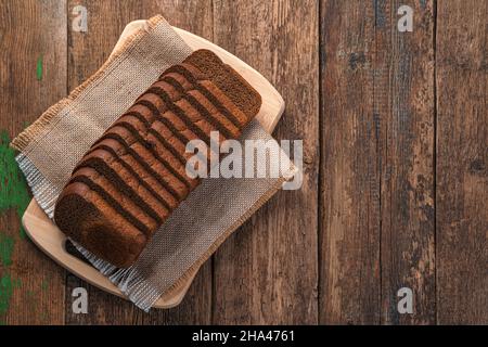 Rye bread cut into pieces on a wooden background. Top view, copy space. Stock Photo