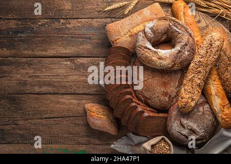 Whole grain, wheat and rye bread in a large assortment on a wooden background. Top view, copy space. Stock Photo