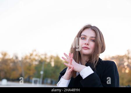 Portrait of attractive long straight haired white european woman in dark coat Stock Photo
