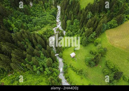 aerial birds eye view showing epic krimml waterfalls surrounded by big forest trees in mountains.