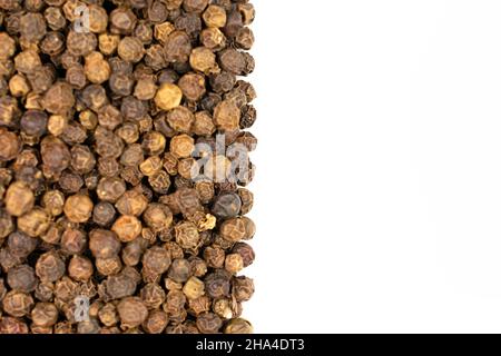 Lot of whole spicy black pepper isolated on white background filling half of frame flatlay Stock Photo