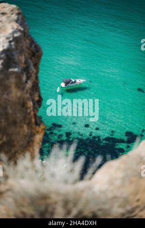 lonely yacht boat moored in bounty lagoon,cape fiolent in balaklava,sevastopol,russia. view from the top of the rock. azure emerald gree sea water on sunny day. vacation summer travel concept. Stock Photo